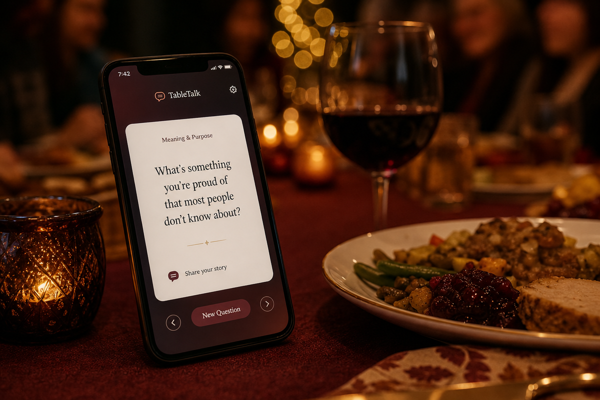 Close-up of a smartphone on a dinner table next to a plate of food and glass of wine, displaying a conversation starter app with a question card, warm bokeh lights in the background