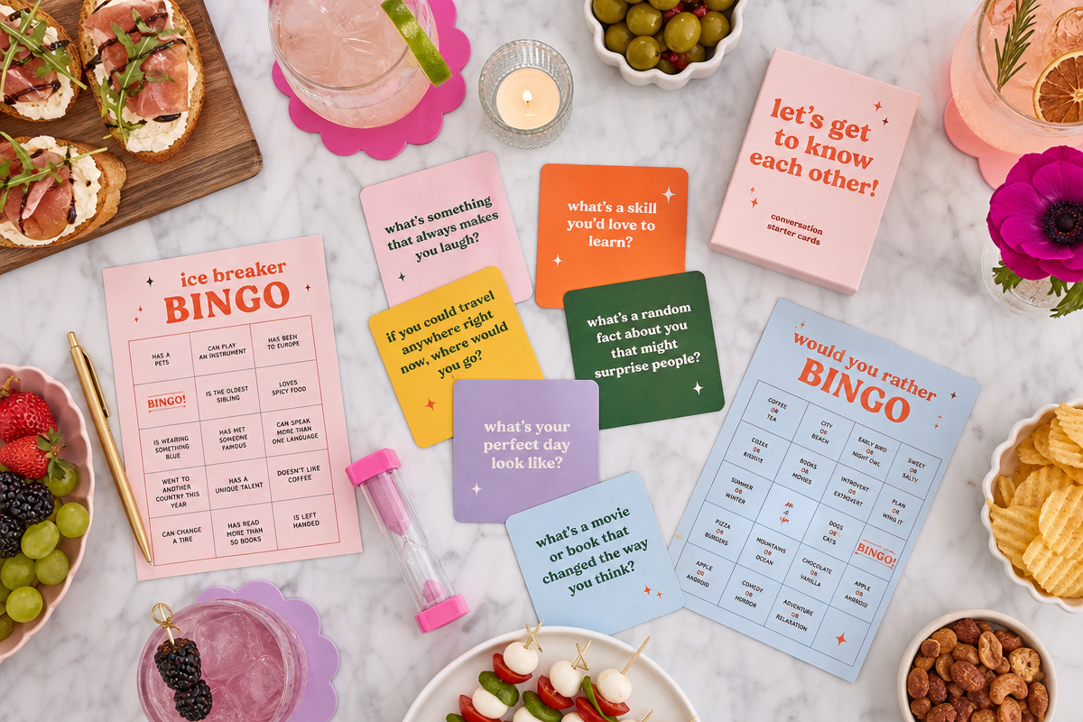 Overhead view of conversation starter cards, bingo game cards, cocktails, and appetizers arranged on a modern party table.